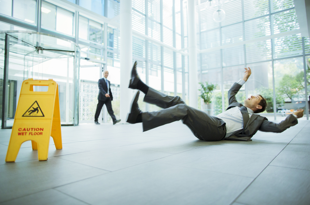 Businessman slipping on floor of office building and looking for personal injury attorney